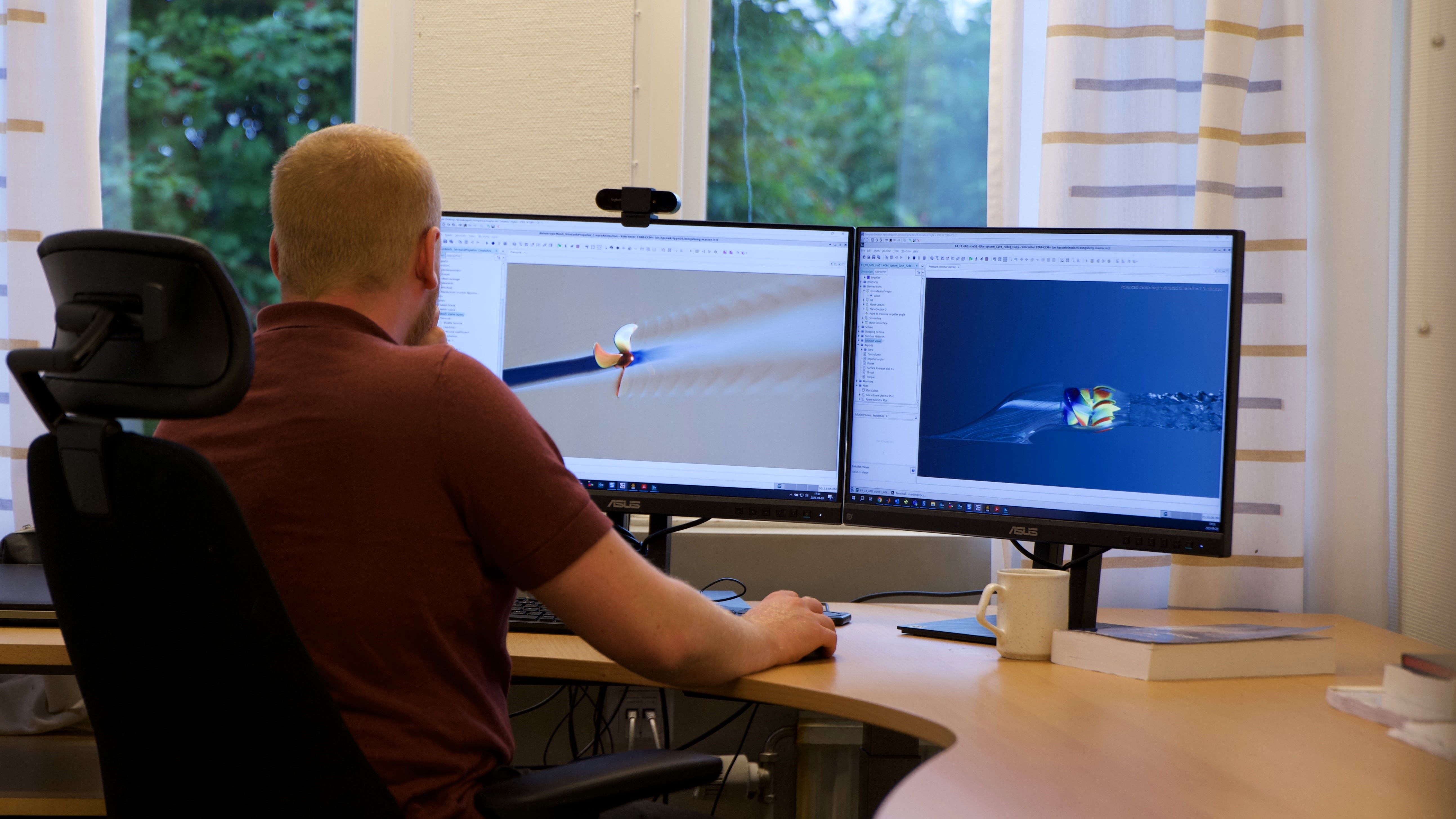 Engineer analysing 3D CFD simulations of a marine propeller on two monitors at an office desk