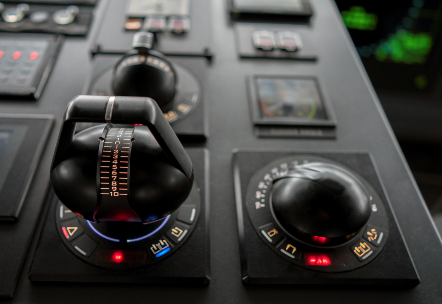 Close-up of a dark, modern control interface featuring a joystick-like lever centered within a circular panel.